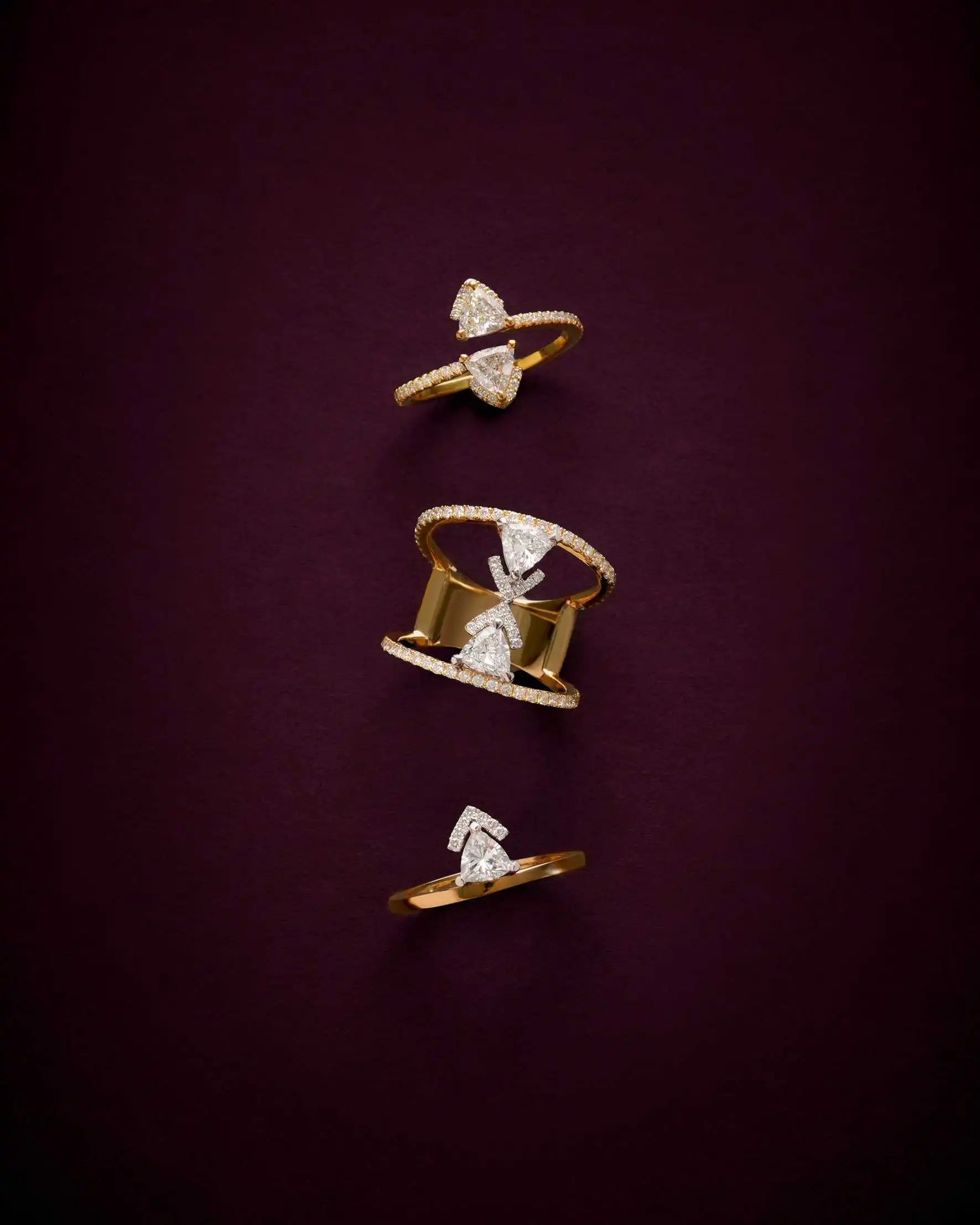 Three lab-grown rings from the Les Angles Collection—Victoria Twins, Victoria Kiss, and Victoria Gold—displayed against a deep aubergine background.