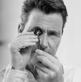 Antony Okker examines a lab-grown diamond with a magnifying glass and specialised tweezers.