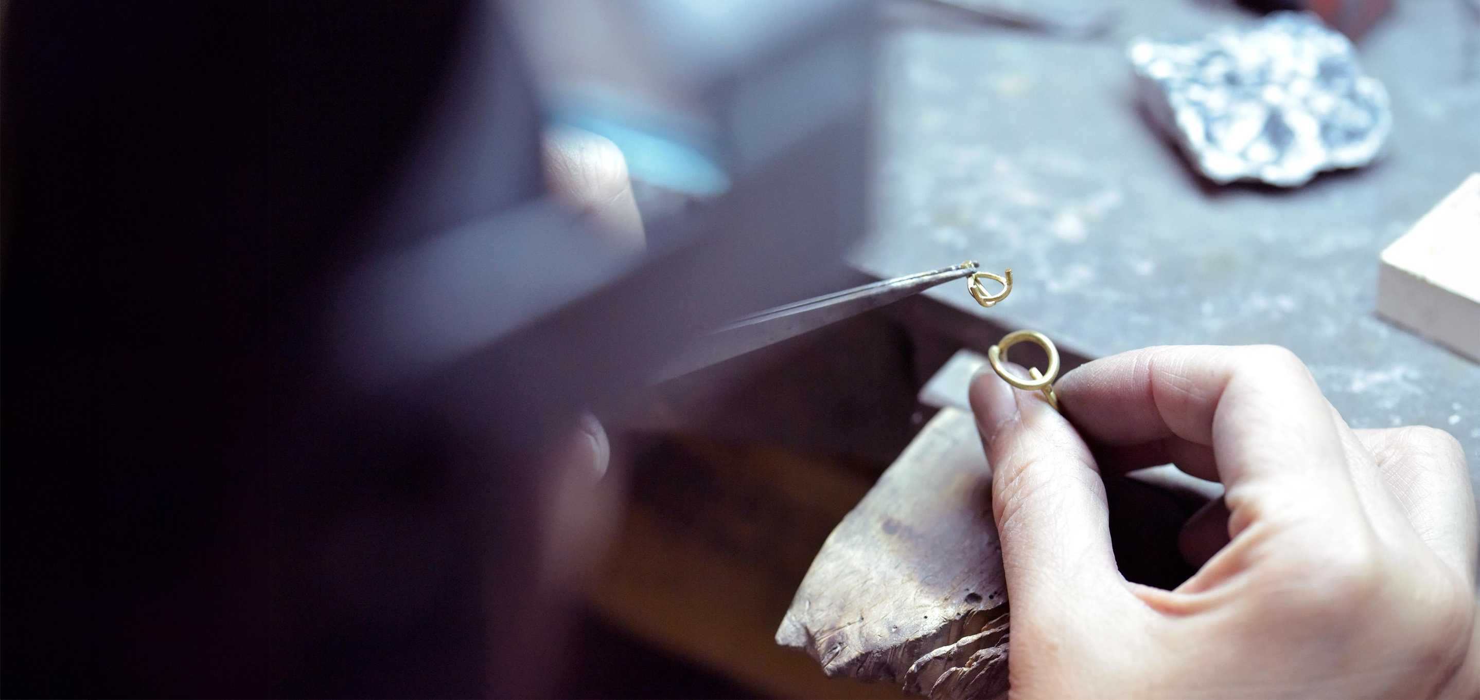 A jeweller carefully assembling the Floating Pear Icon ring in the atelier, using precision tools to craft the gold setting.
